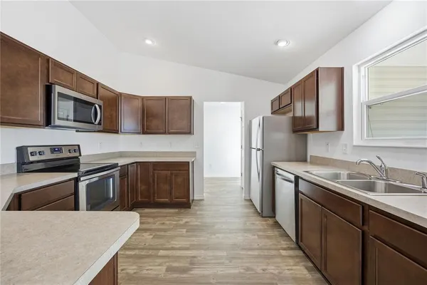 a kitchen with stainless steel appliances granite countertop a stove top oven a sink and dishwasher a oven with wooden cabinets