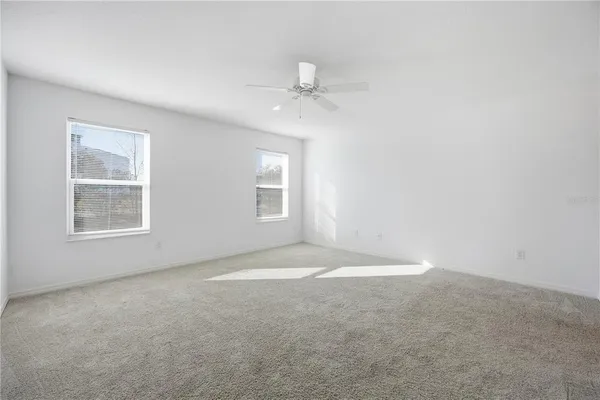 an empty room with windows and ceiling fan