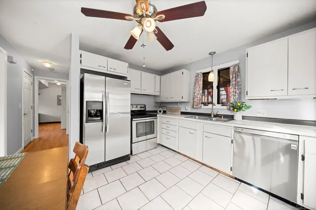 a kitchen with granite countertop a refrigerator oven a sink and white cabinets
