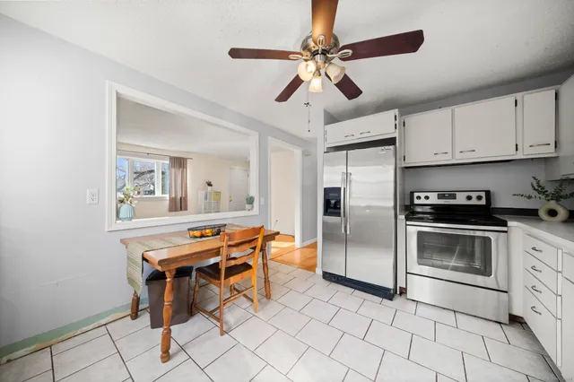 a kitchen with stainless steel appliances kitchen island granite countertop a stove a sink and a refrigerator with white cabinets