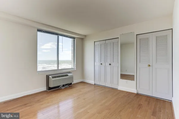 a view of empty room with wooden floor and fan