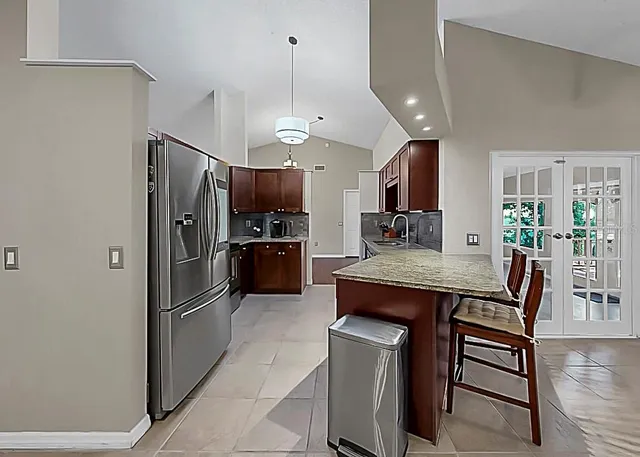 a kitchen with stainless steel appliances a refrigerator a stove a sink a dining table and chairs