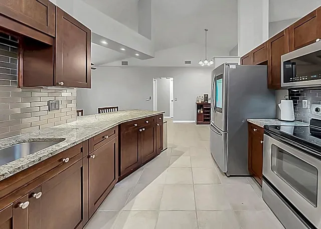 a large kitchen with stainless steel appliances granite countertop a refrigerator and a sink