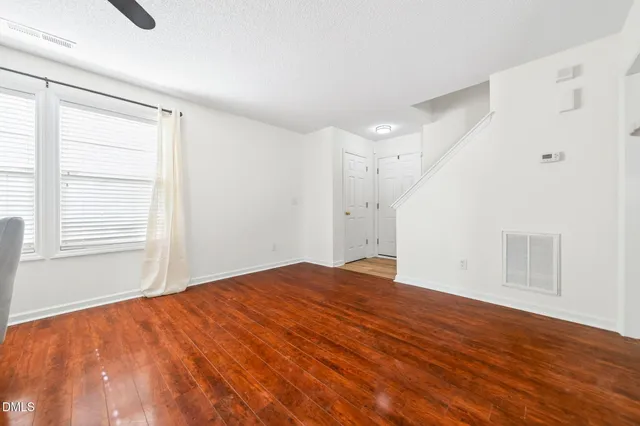 a view of empty room with wooden floor and fan