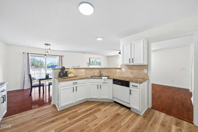 a kitchen with granite countertop a sink cabinets and wooden floor