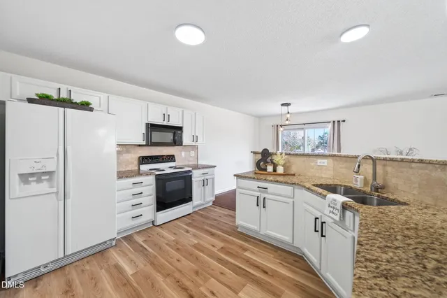 a kitchen with granite countertop a sink stove and refrigerator