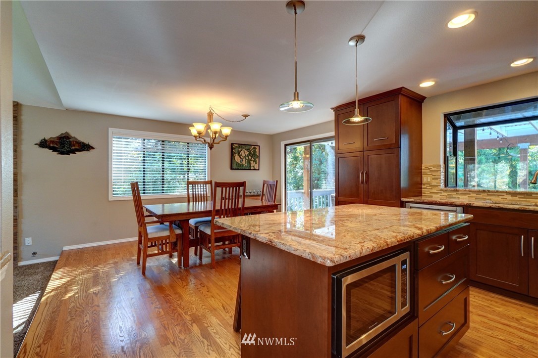 2831 Whitworth Avenue South Renton, WA 98055 - Photo 11 of 40 a kitchen with stainless steel appliances granite countertop sink stove dining table chairs and wooden floor