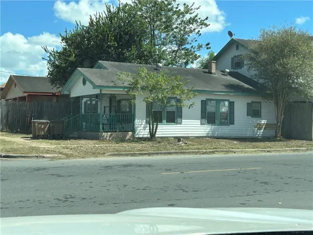 a view of a white house with a yard and large tree