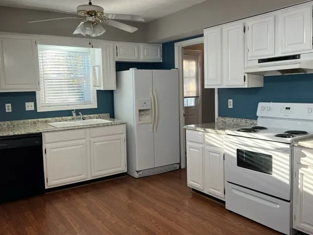 a kitchen with a stove cabinets and wooden floor