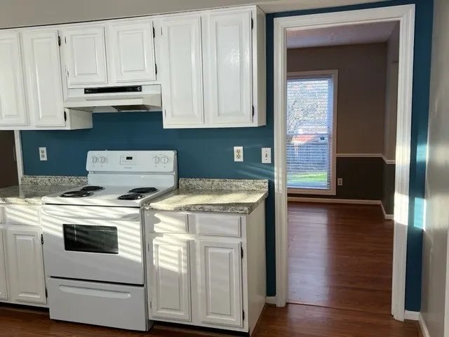 a kitchen with granite countertop white cabinets and white appliances