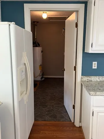 a view of a storage and utility room with refrigerator and wooden floor