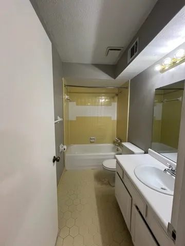 a bathroom with a granite countertop sink a mirror and a bathtub
