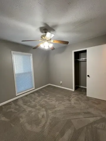 a view of an empty room with a chandelier fan