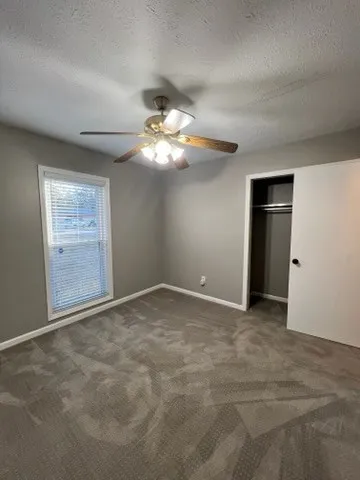 a view of an empty room with a chandelier fan