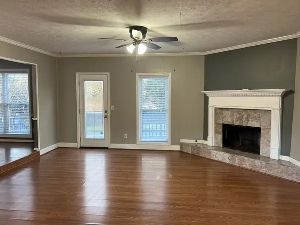 a view of an empty room with wooden floor fireplace and a window