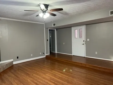 a view of an empty room with window and wooden floor