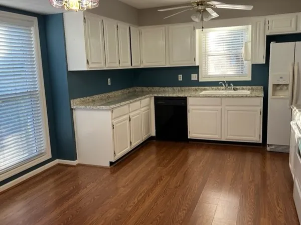 a kitchen with granite countertop wooden floors stainless steel appliances and sink