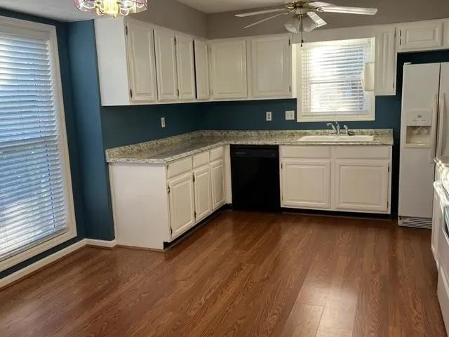 a kitchen with granite countertop wooden floors stainless steel appliances and sink