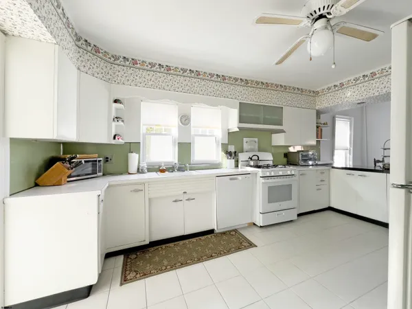 a kitchen that has a lot of white cabinets and stainless steel appliances