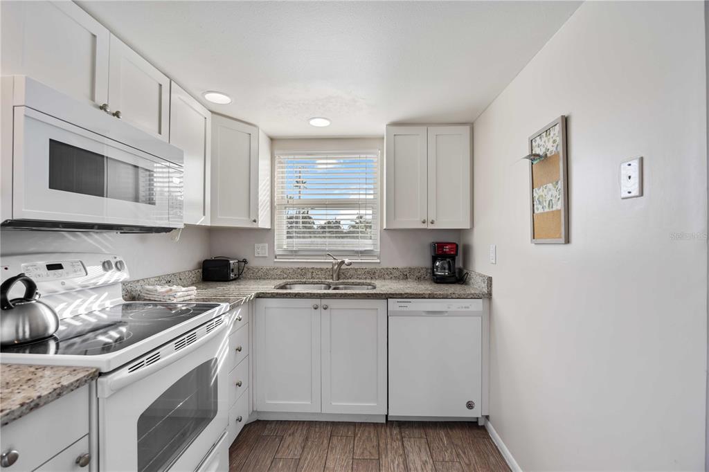 6150 Midnight Pass Road, Unit 10 A&B Sarasota, FL 34242 - Photo 34 of 65 a kitchen with granite countertop white cabinets and white appliances