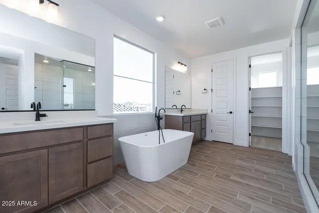 a spacious bathroom with a double vanity sink a mirror and a bathtub