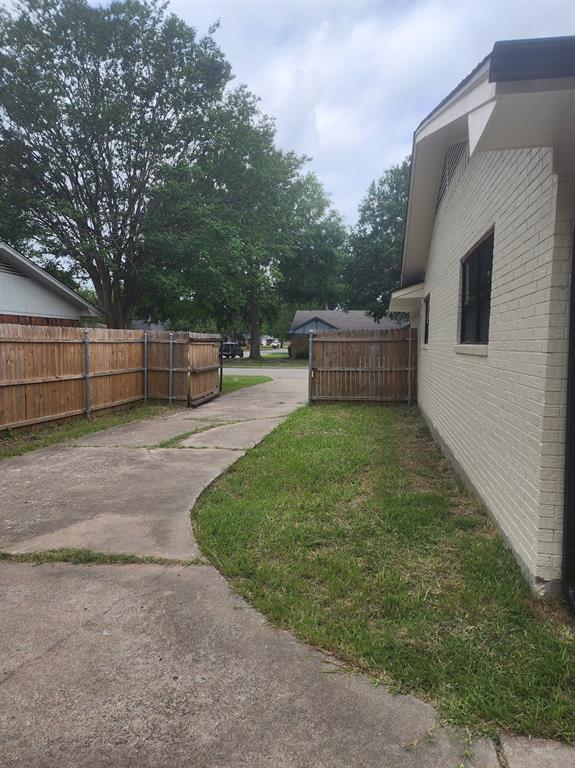 2908 Washington Street Commerce, TX 75428 - Photo 27 of 29 Side yard featuring a concrete driveway, established grass area, and a wood privacy fence