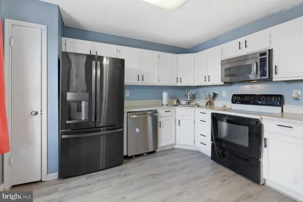 a kitchen with cabinets stainless steel appliances and wooden floor