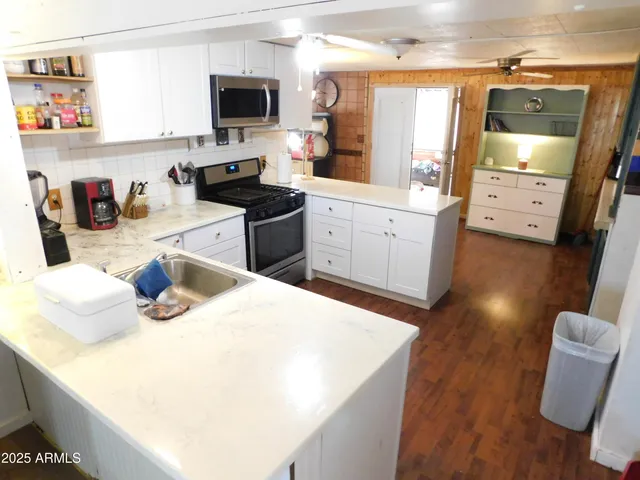 a kitchen with stainless steel appliances kitchen island granite countertop a sink dishwasher stove and white countertops with wooden floor