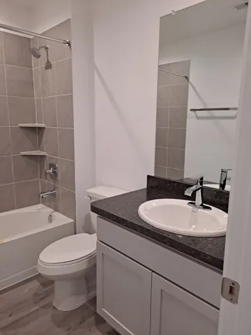 a bathroom with a granite countertop sink toilet a mirror and shower