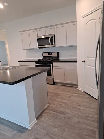 a kitchen with stainless steel appliances granite countertop a refrigerator stove top oven and sink