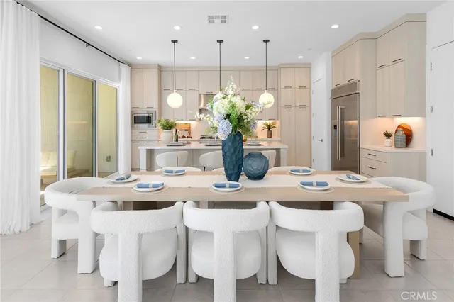 a dining room with stainless steel appliances kitchen island a table chairs and kitchen view