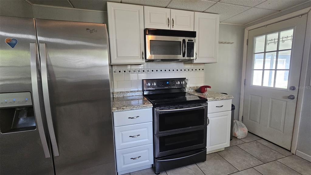 36850 Haynes Road Fruitland Park, FL 34731 - Photo 10 of 28 a kitchen with stainless steel appliances white cabinets and a stove top oven