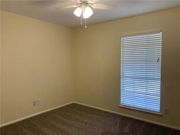 an empty room with a chandelier fan and a window