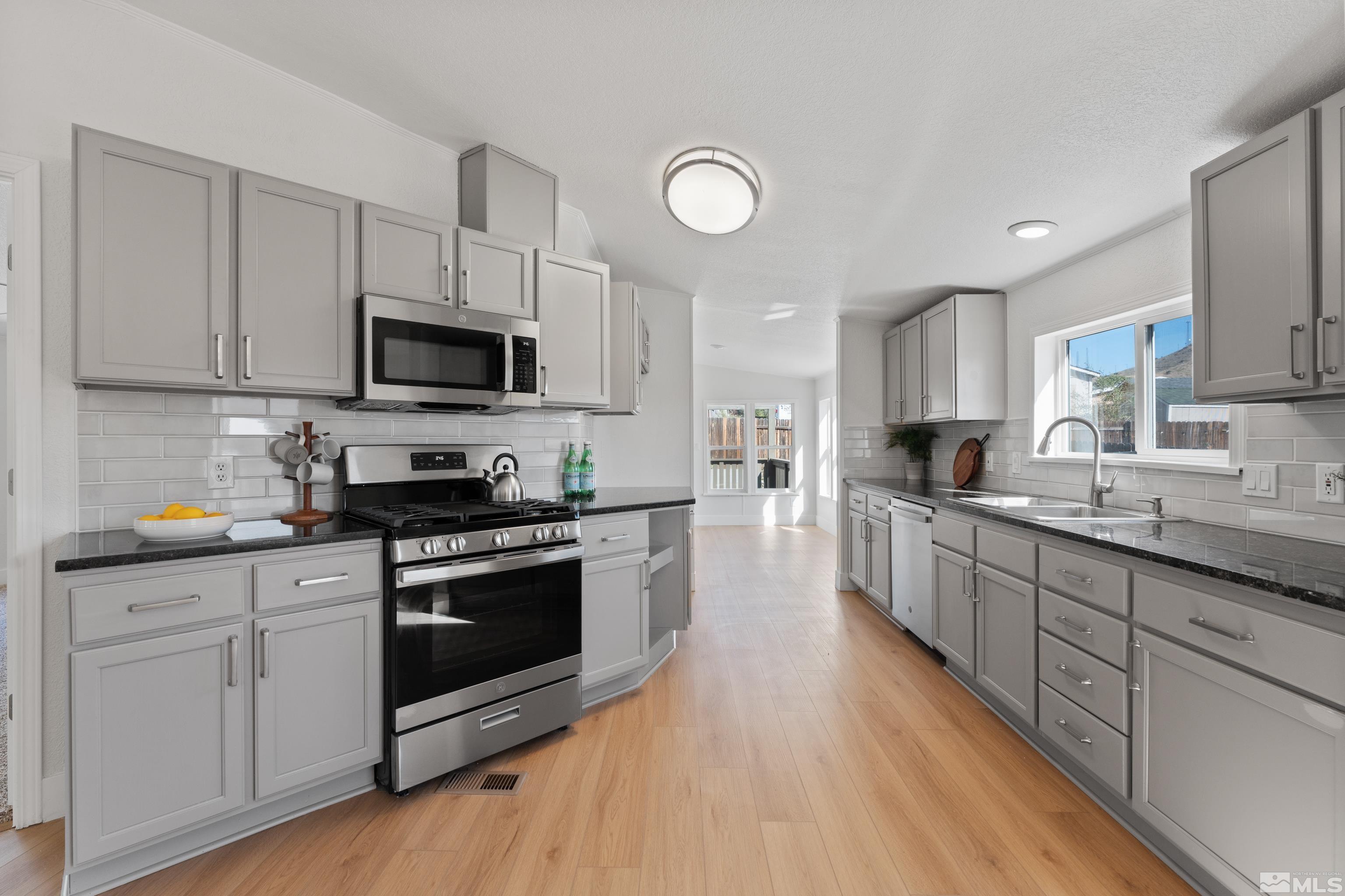 7640 Lytton Road Reno, NV 89506 - Photo 4 of 40 a large kitchen with stainless steel appliances granite countertop a stove a sink dishwasher and a microwave oven with wooden floor