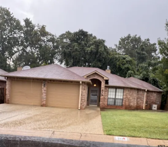a front view of a house with a garden and trees