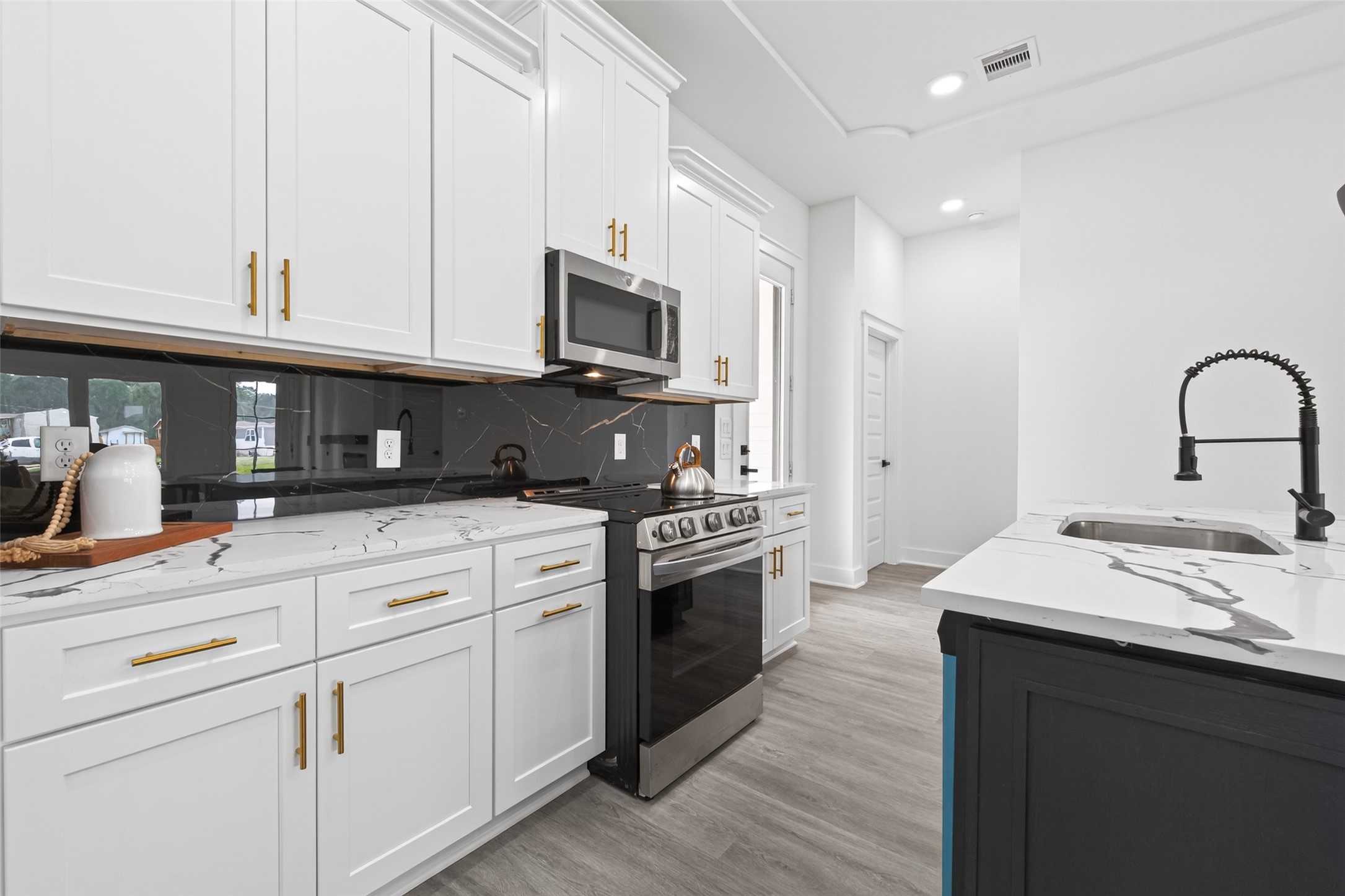 1129 Longleaf Pne Street Huffman, TX 77336 - Photo 8 of 35 a kitchen with stainless steel appliances granite countertop a stove a sink dishwasher and a microwave oven with white cabinets