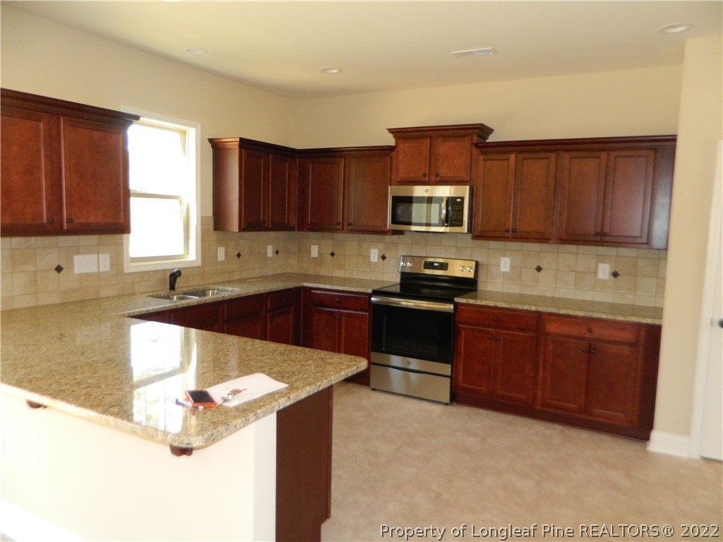 22 Raintree Lane Spring Lake, NC 28390 - Photo 10 of 33 a kitchen with granite countertop a stove microwave and sink