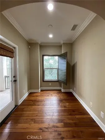 a view of an empty room with wooden floor and a window