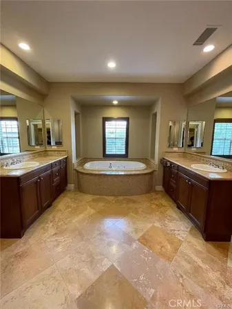 a spacious bathroom with a tub double sink and mirror