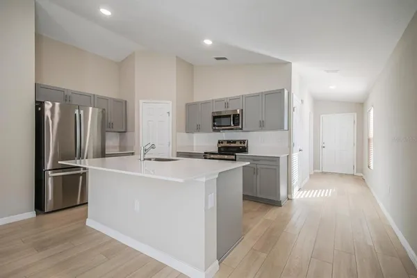 a large kitchen with a center island wooden floor stainless steel appliances and cabinets