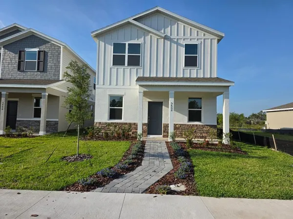 a front view of a house with a yard and potted plants