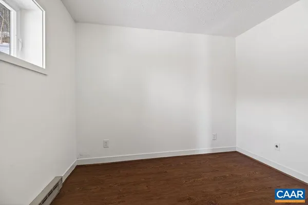 a view of an empty room with wooden floor and stairs