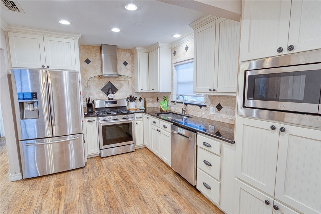 1202 Crosby Street Portland, TX 78374 - Photo 8 of 20 a kitchen with granite countertop a refrigerator oven a sink and white cabinets