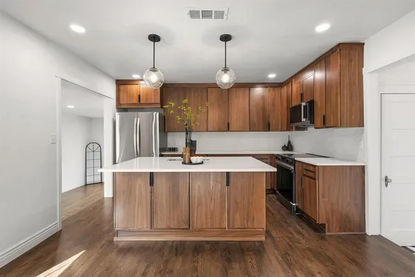 a large kitchen with stainless steel appliances granite countertop a sink a stove and a wooden floors