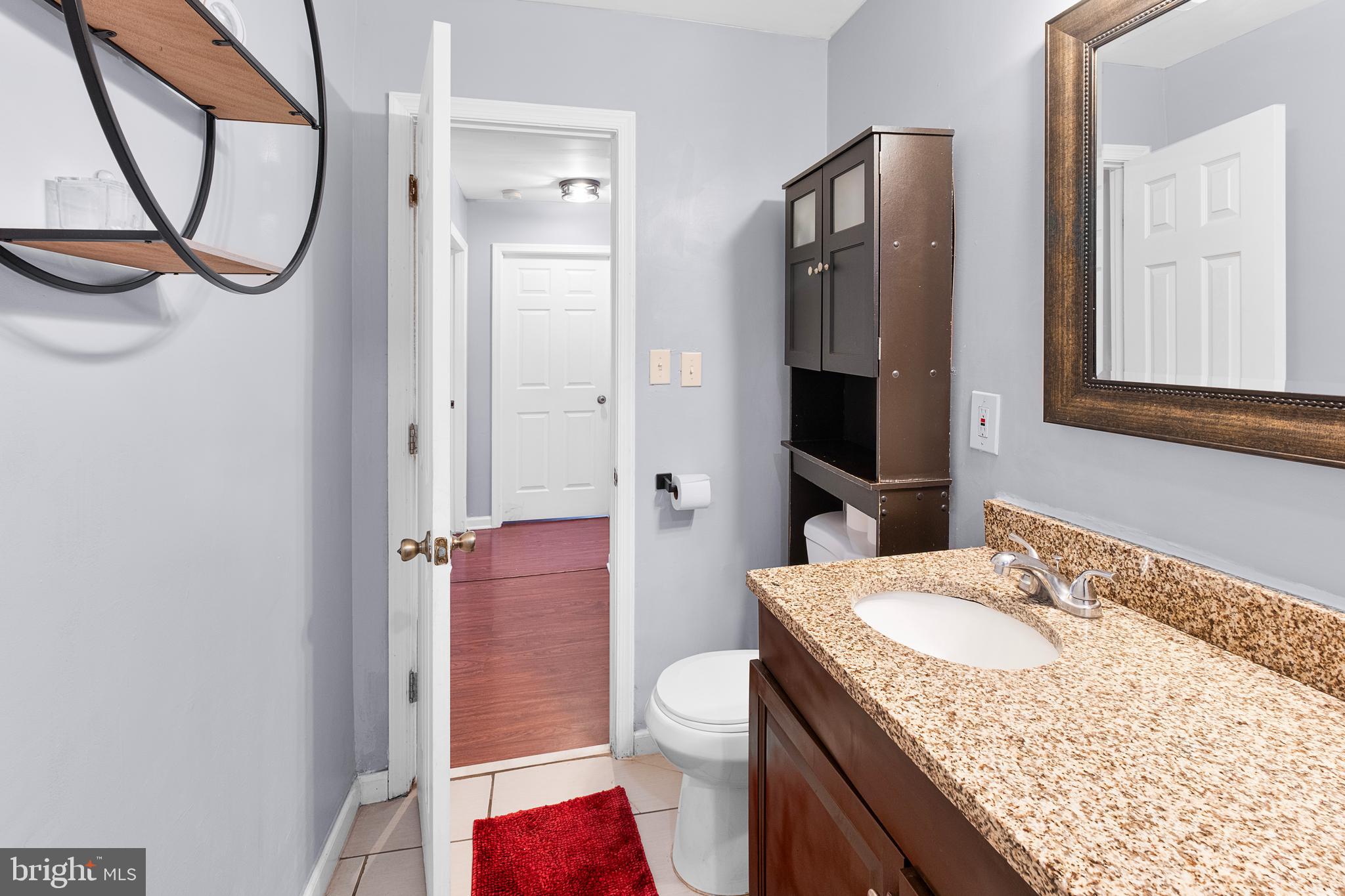 2208 Virginia Avenue Landover, MD 20785 - Photo 11 of 17 a bathroom with a granite countertop sink a toilet and a mirror