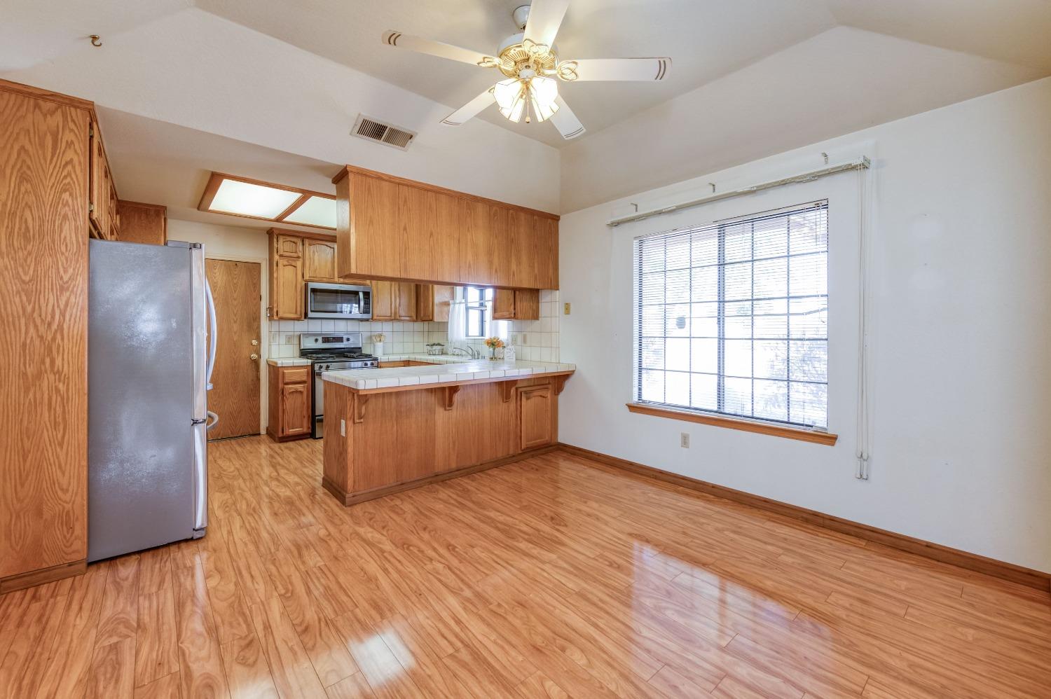 19650 Road 31 Madera, CA 93638 - Photo 10 of 43 a kitchen with stainless steel appliances kitchen island granite countertop a refrigerator a sink dishwasher a stove with wooden cabinets and floor