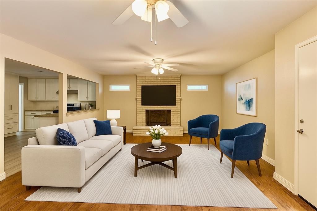 Living room with light wood-style flooring, a brick fireplace, plenty of natural light, and a ceiling fan