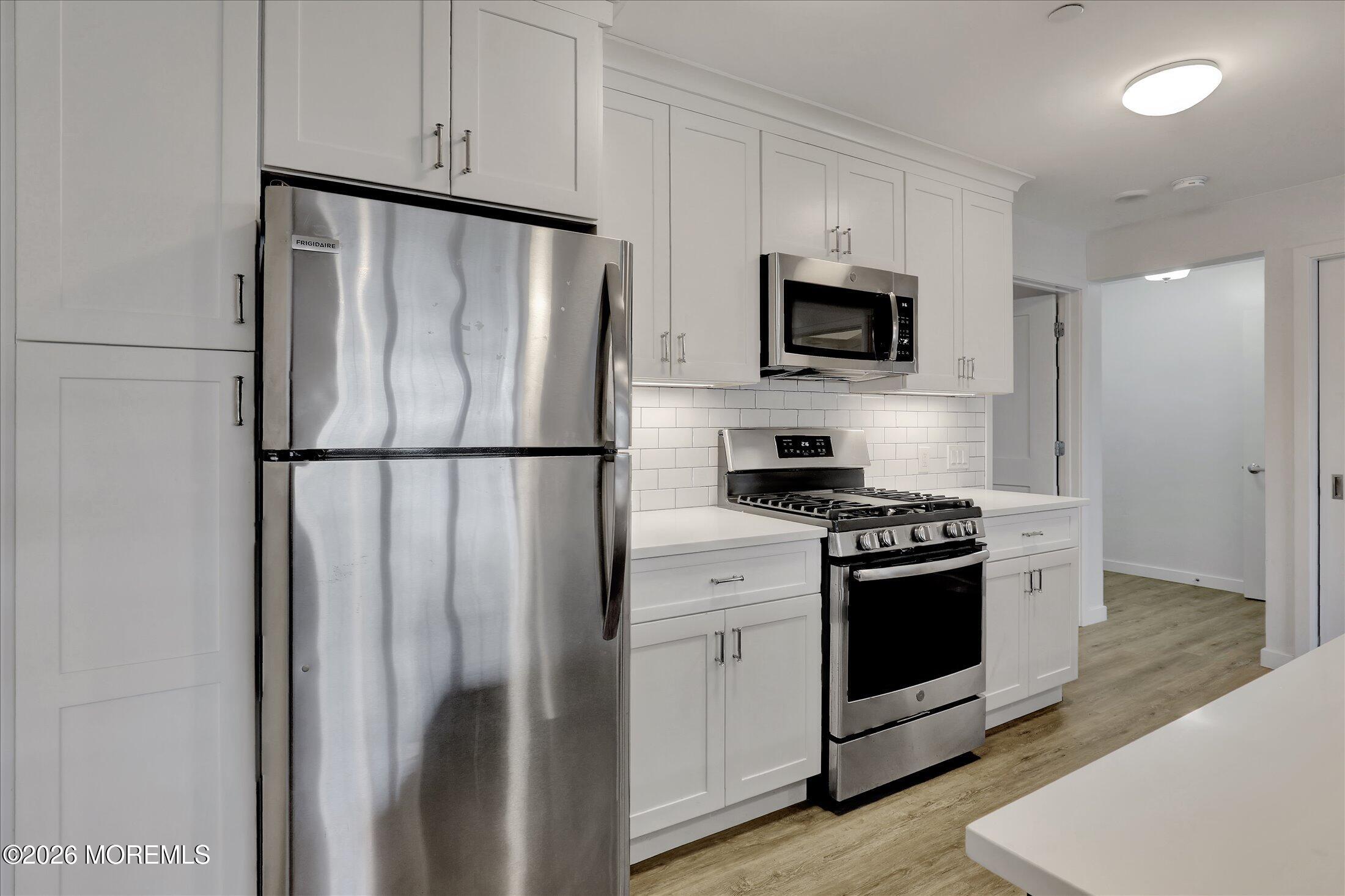 55 Brighton Avenue, Unit 4 Long Branch, NJ 07740 - Photo 11 of 36 a kitchen with stainless steel appliances granite countertop a refrigerator stove a sink and a microwave