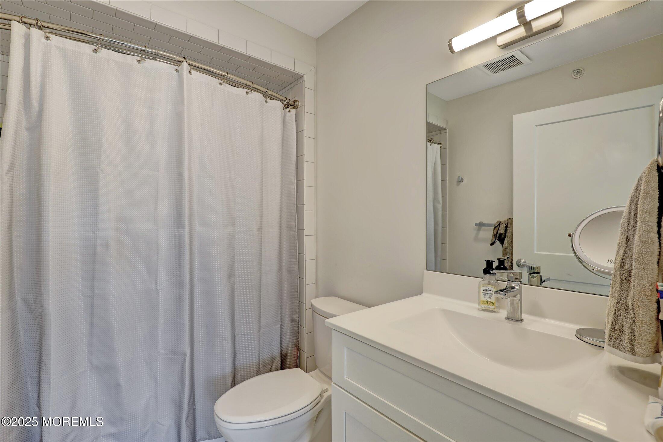 55 Brighton Avenue, Unit 4 Long Branch, NJ 07740 - Photo 11 of 33 a bathroom with a sink a toilet and shower curtain