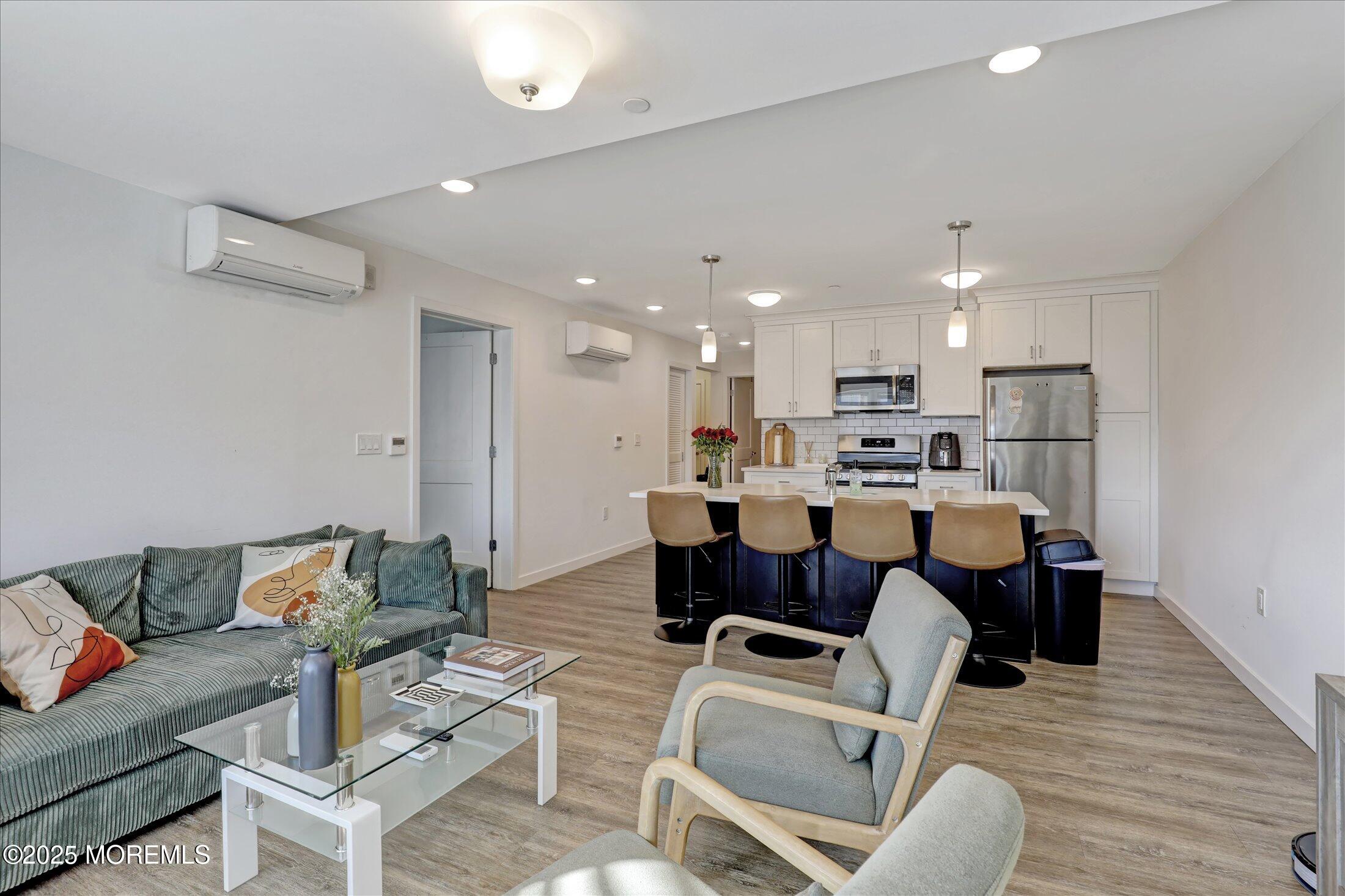 55 Brighton Avenue, Unit 4 Long Branch, NJ 07740 - Photo 6 of 33 a living room with a couch and a dining table with wooden floor